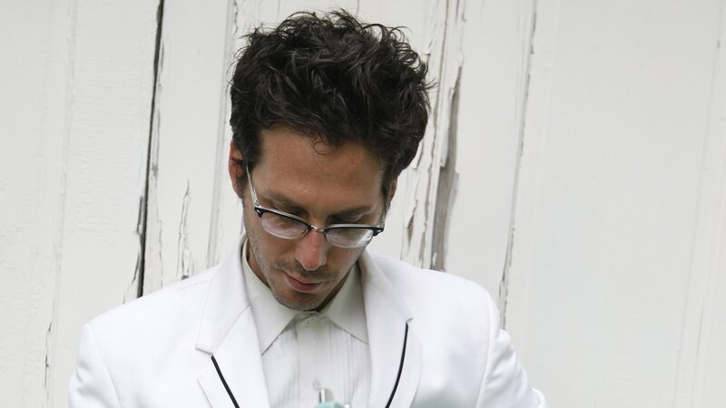 man in white suit looking down