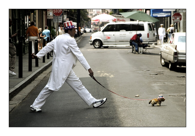 Man in white suit walking dog