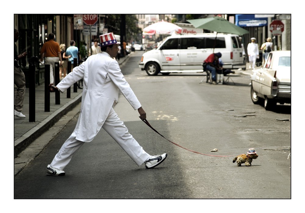 Man in white suit walking dog