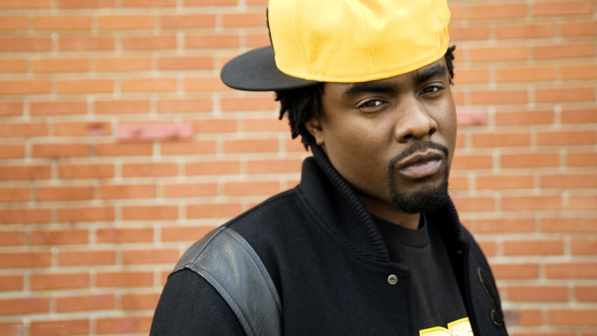 man in yellow cap against brick wall