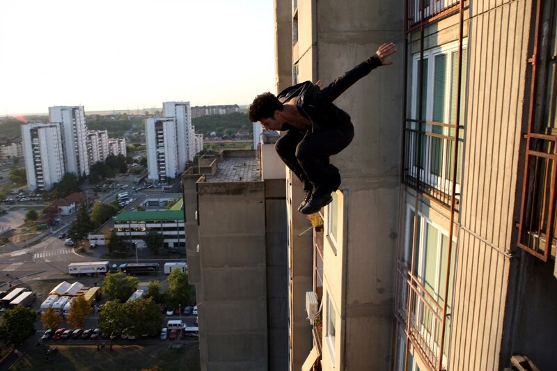 Man Jumping Between Buildings — Gray, Dramatic