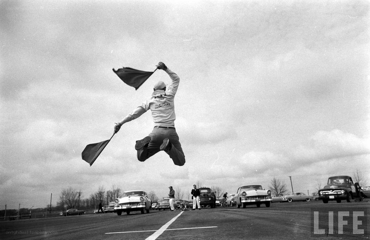 Man jumping with flag at race track
