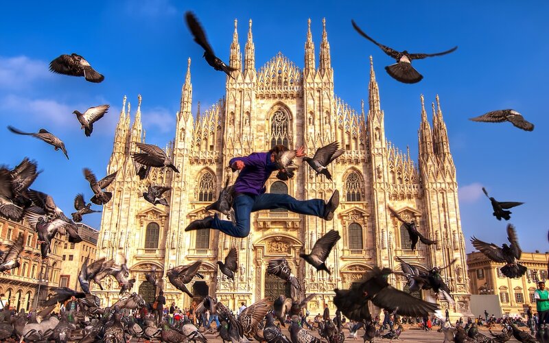 Man jumping with pigeons at Duomo