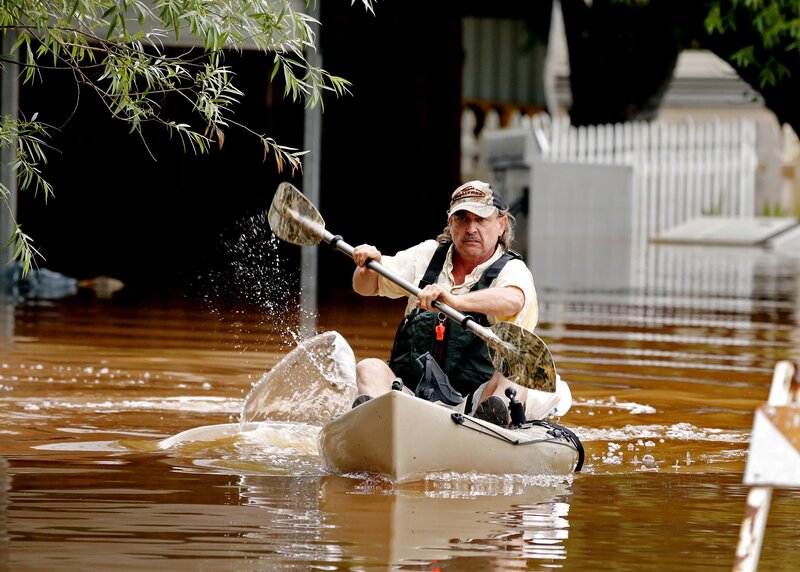 Man kayaking through floodwaters