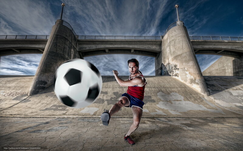 Man kicking soccer ball under bridge