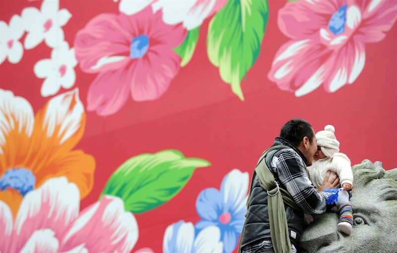 Man kissing baby on wall