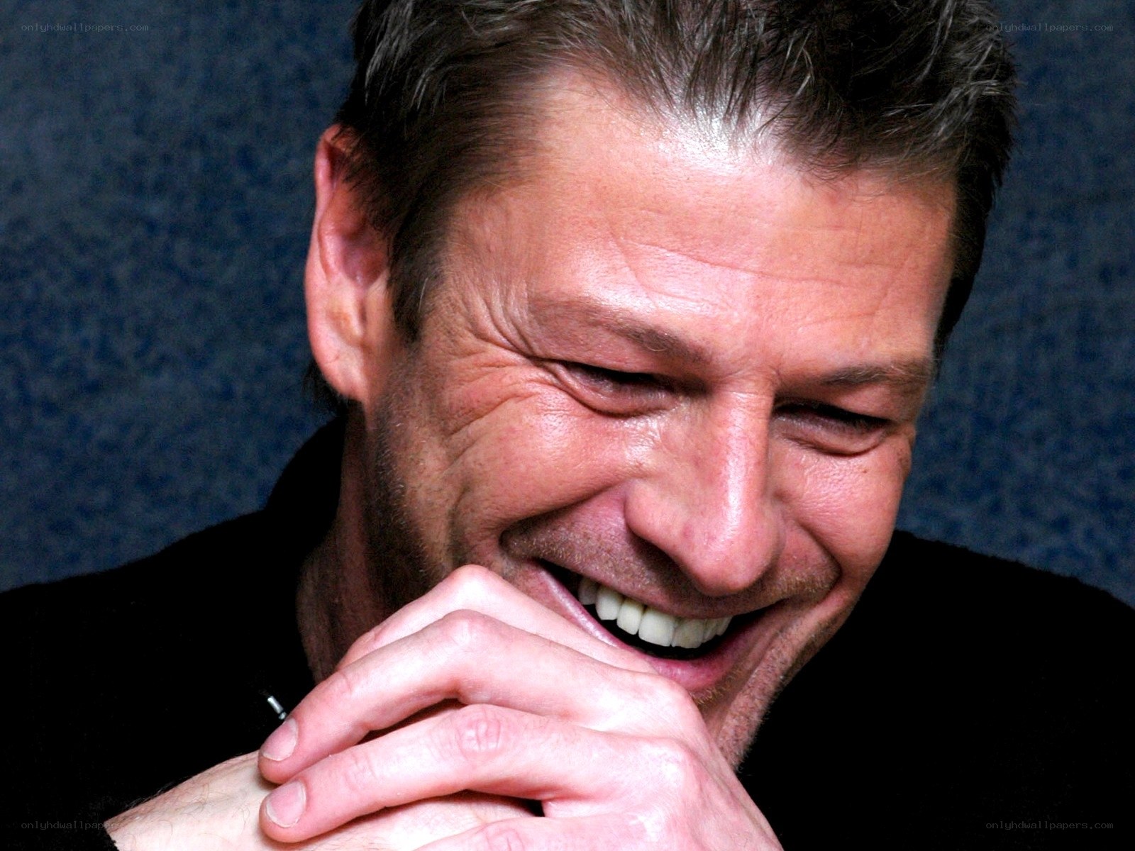 man laughing with hands clasped