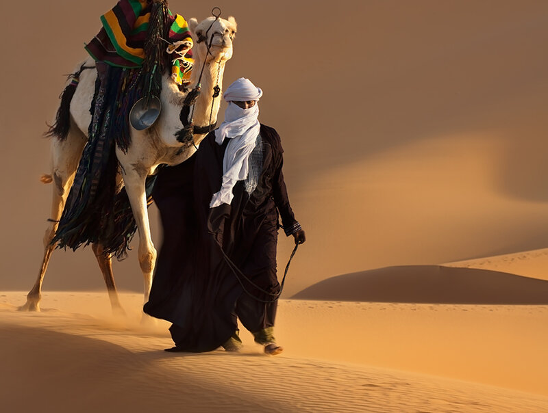 Man Leading Camel in Desert