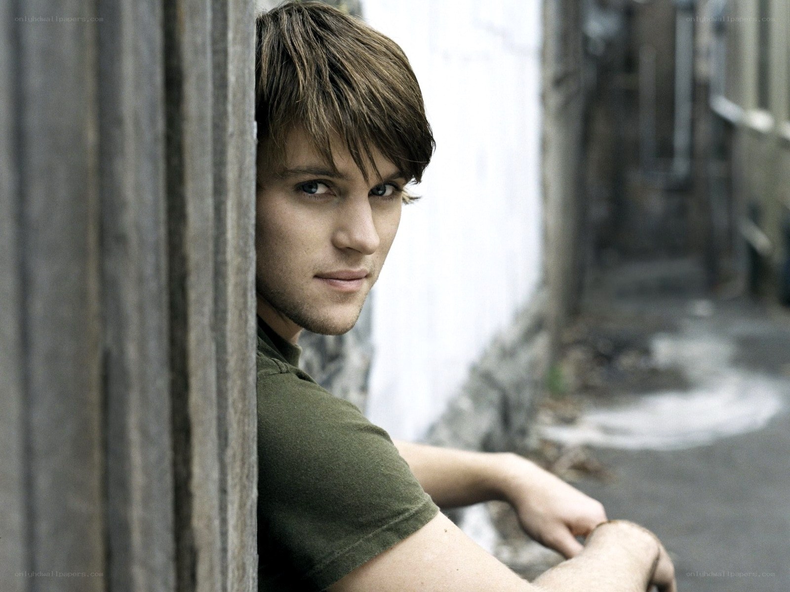 man leaning against wooden wall