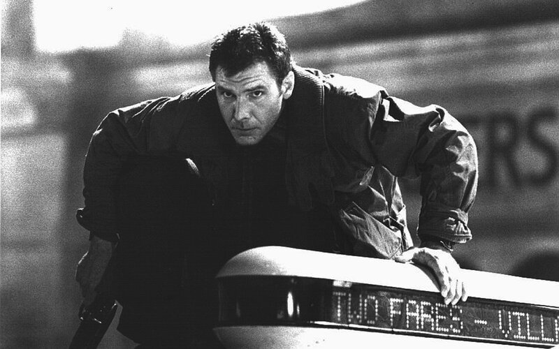 man leaning on car in black and white
