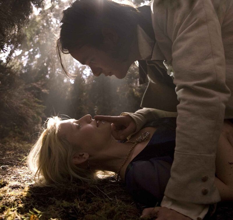 man leaning over woman in forest