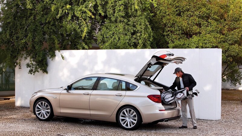 man loading golf bag into car