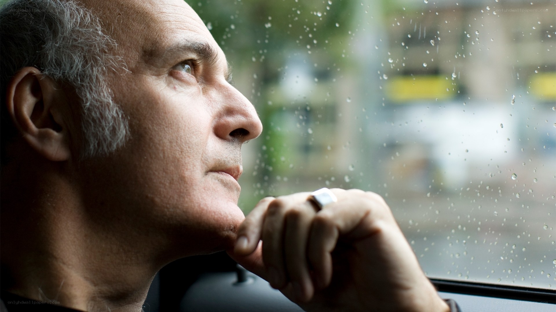 man looking out rainy window