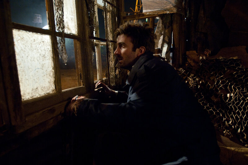 man looking out window at night