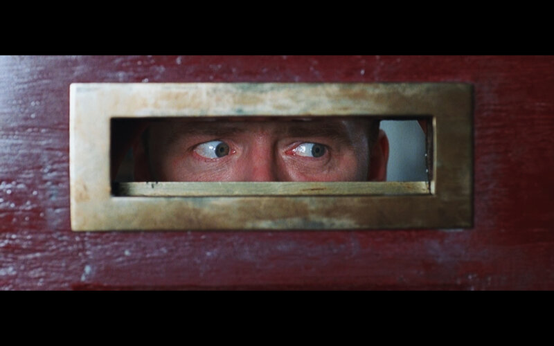 man looking through door slot