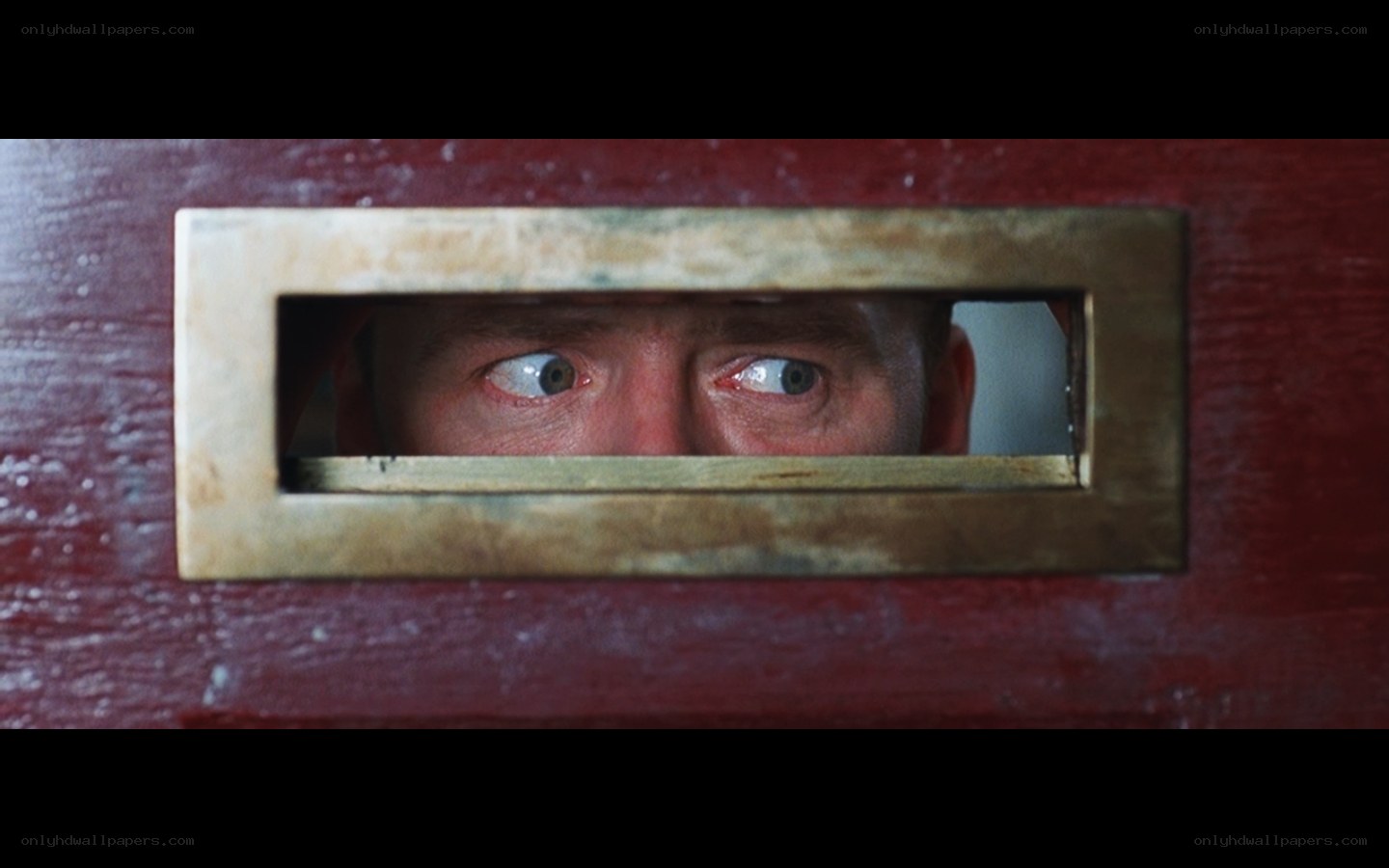 man looking through door slot