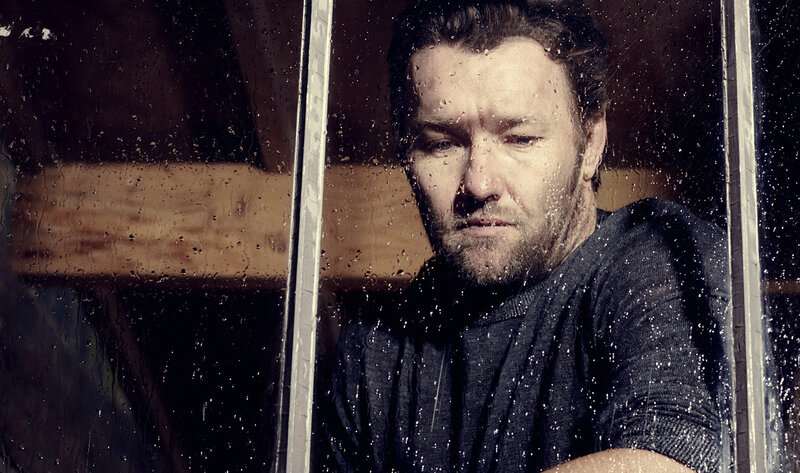 man looking through rain-streaked window