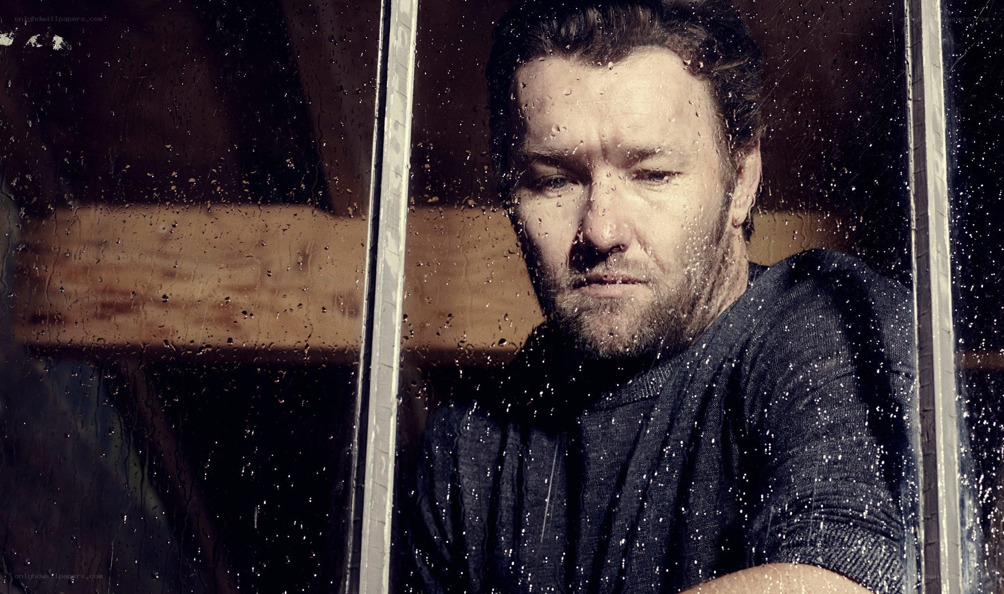 man looking through rain-streaked window