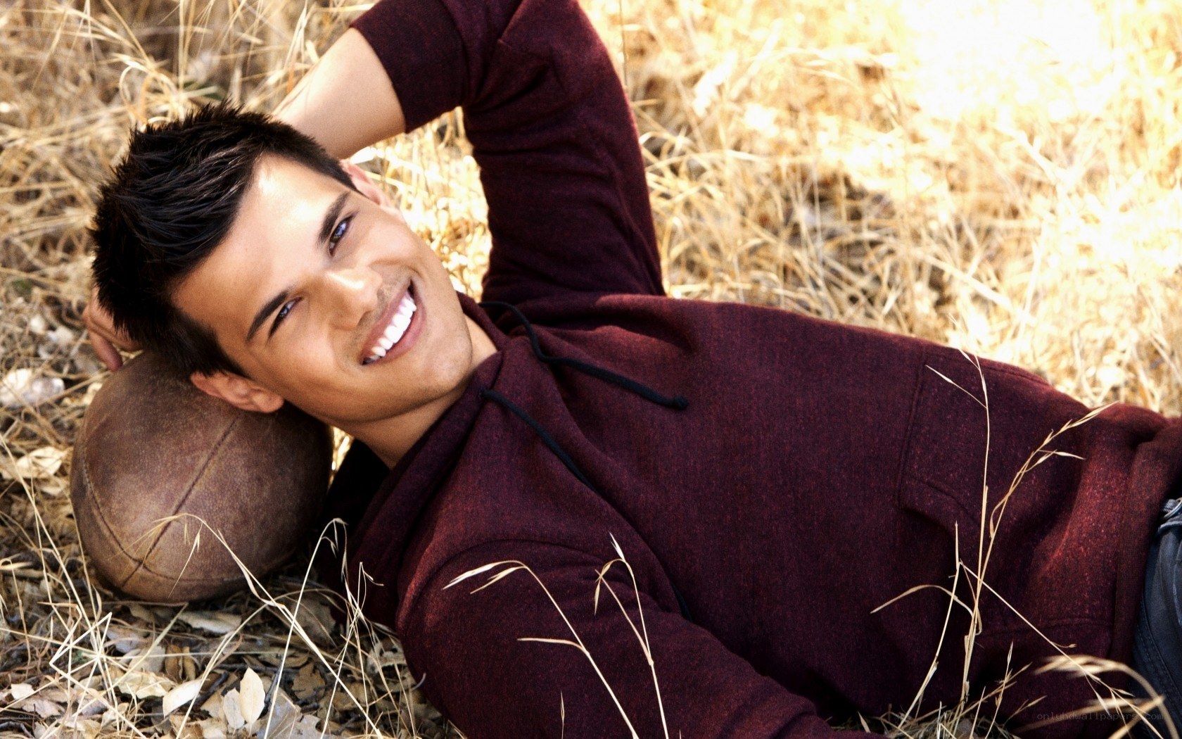 man lying in grass with football