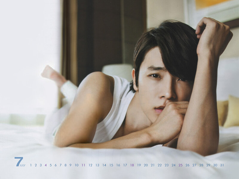 man lying on bed in white tank top