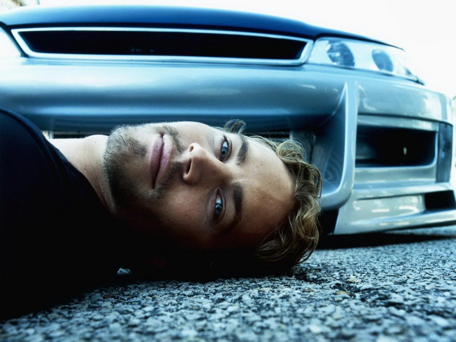 man lying on ground near car