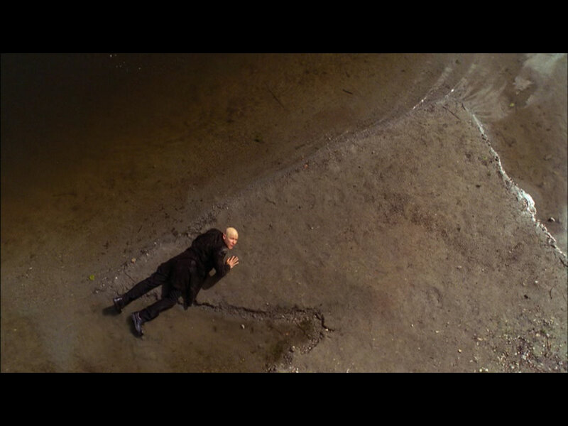 man lying on ground near water