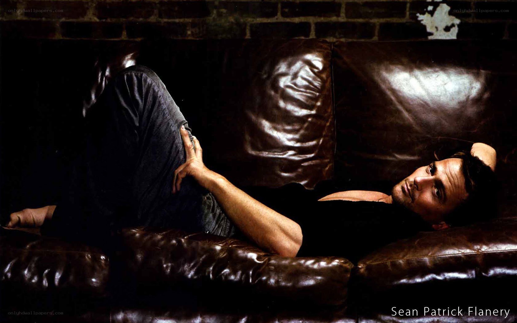 man lying on leather couch