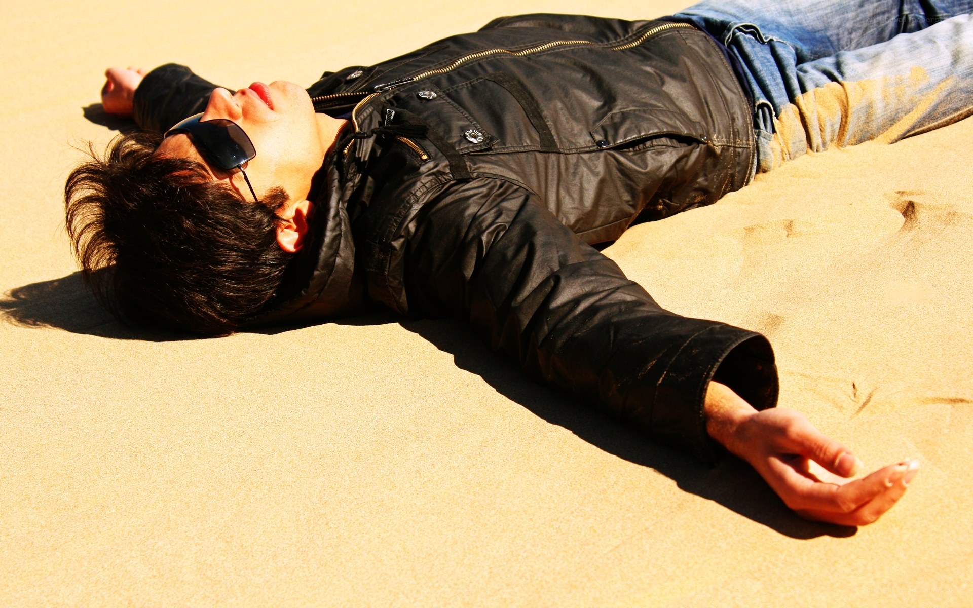 Man lying on sand in sunglasses
