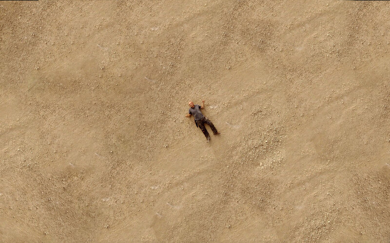 Man lying on sandy ground