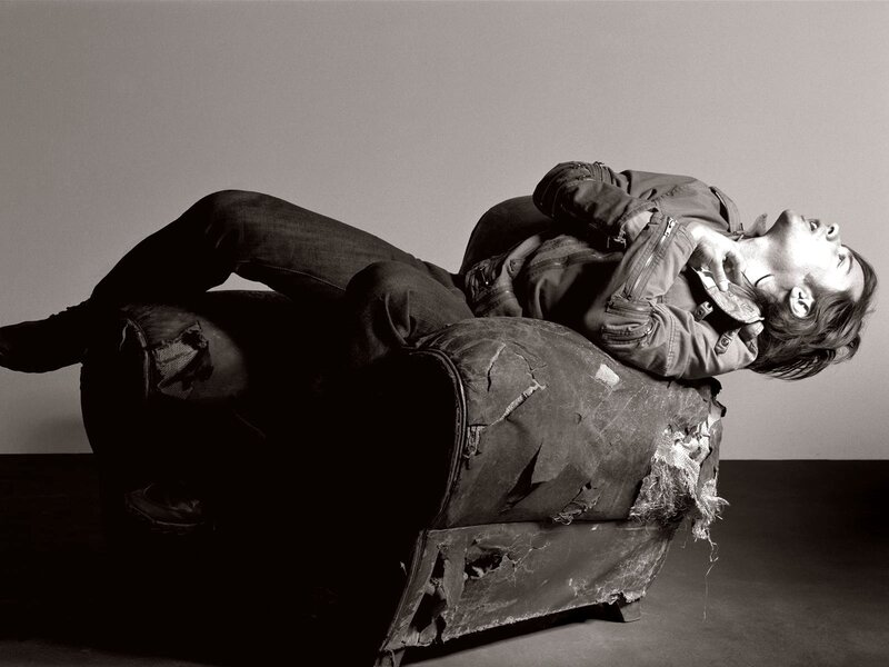 man lying on torn couch