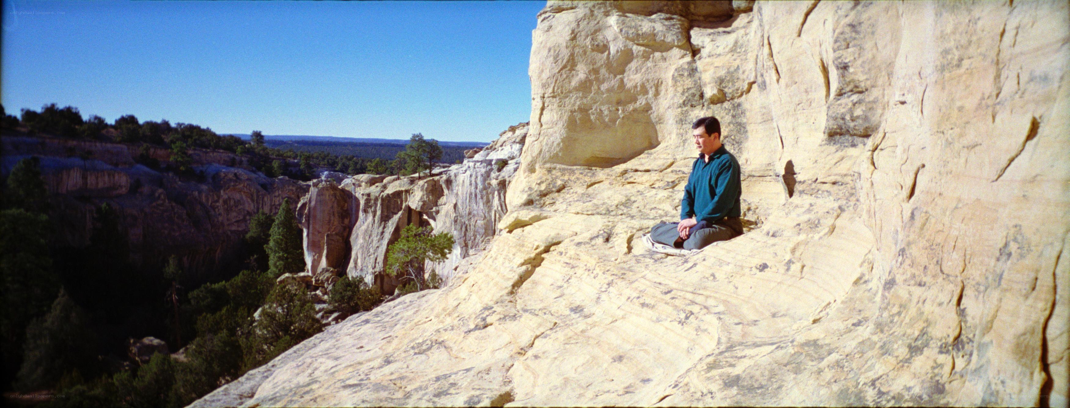Man meditating on a cliff