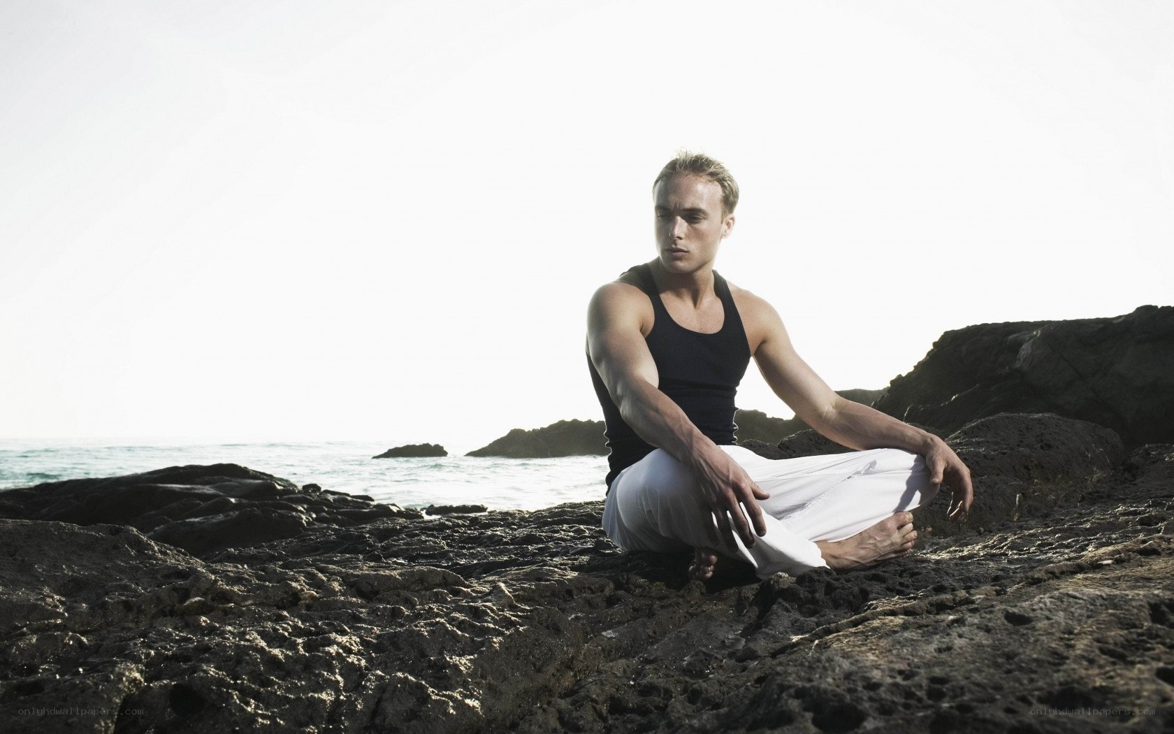 Man meditating on rocky shore