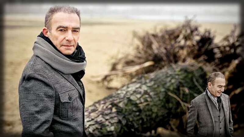 man on a beach with driftwood