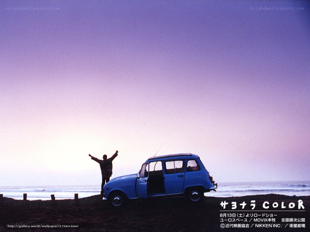 Man on beach with blue car