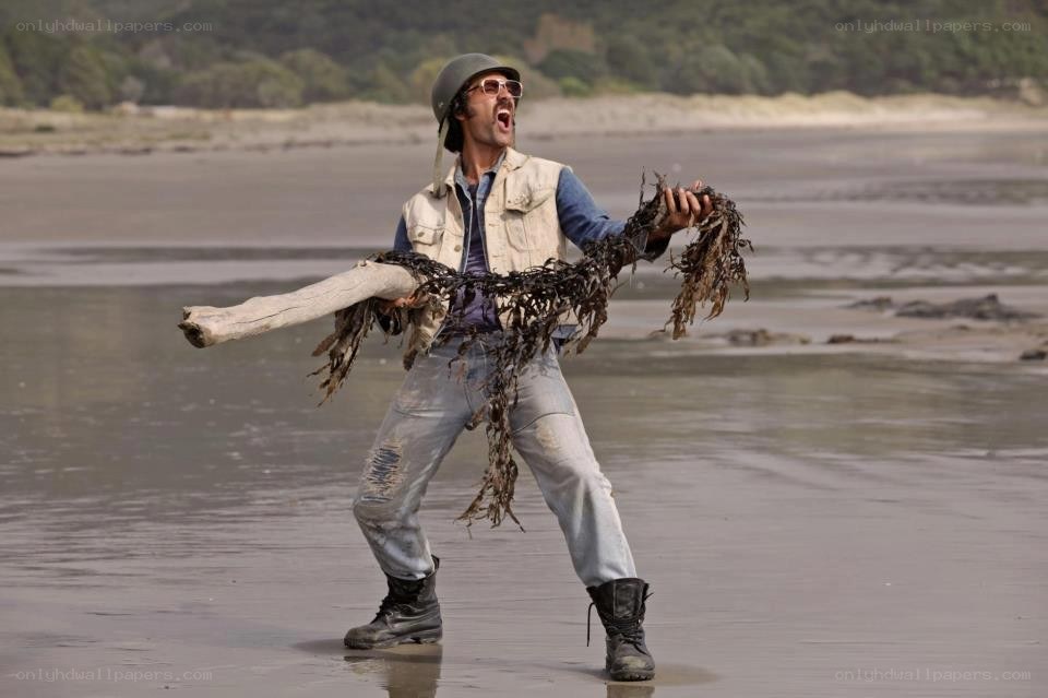 man on beach with driftwood