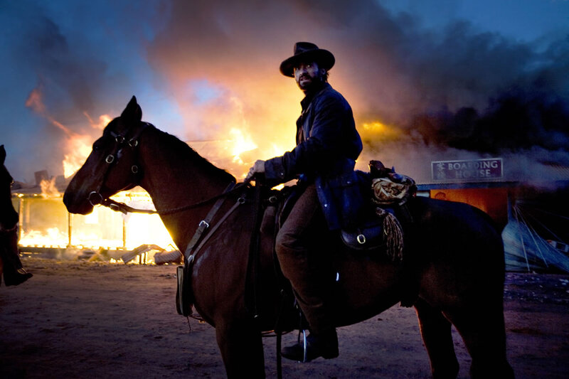 Man on horseback in burning town