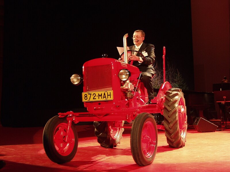 Man on red tractor on stage