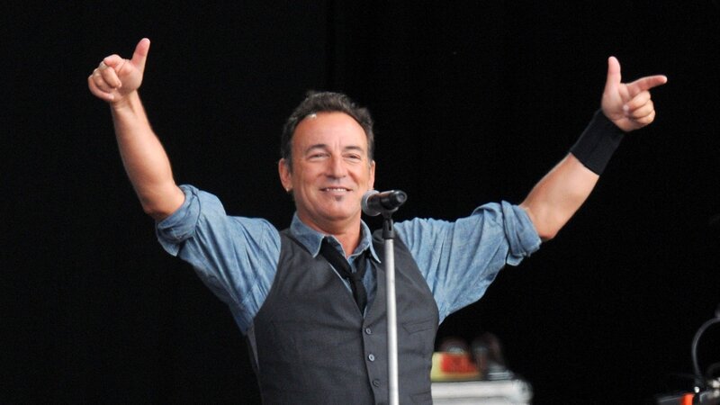 Man on Stage with Arms Raised — Black