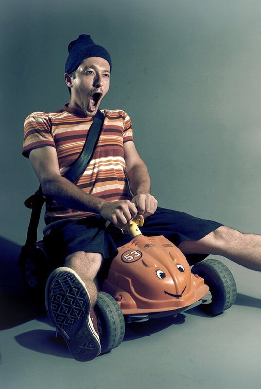 Man on toy car with open mouth