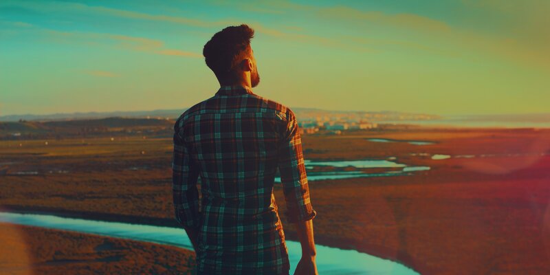 Man overlooking a river at sunset