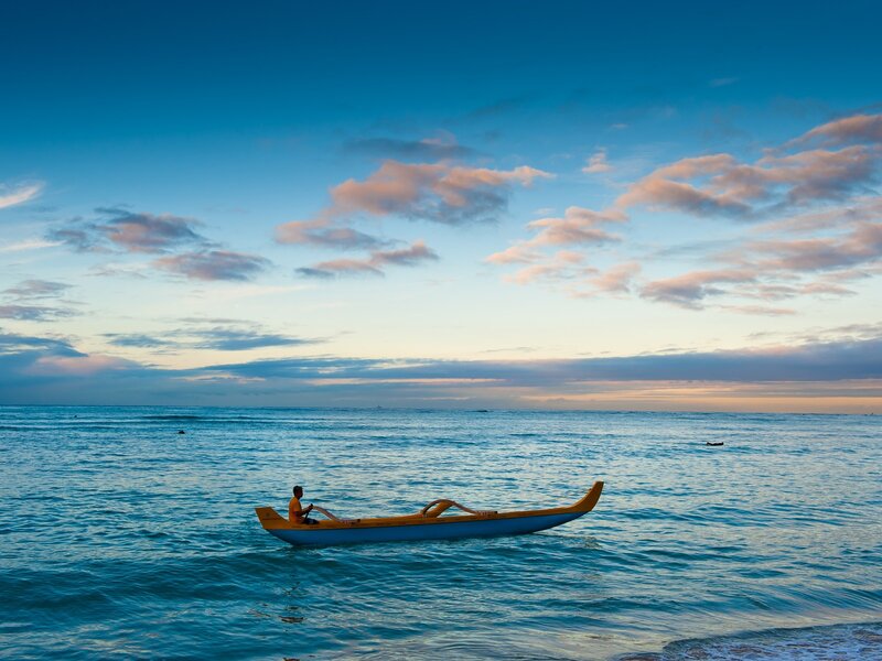 Man paddling canoe at sunset