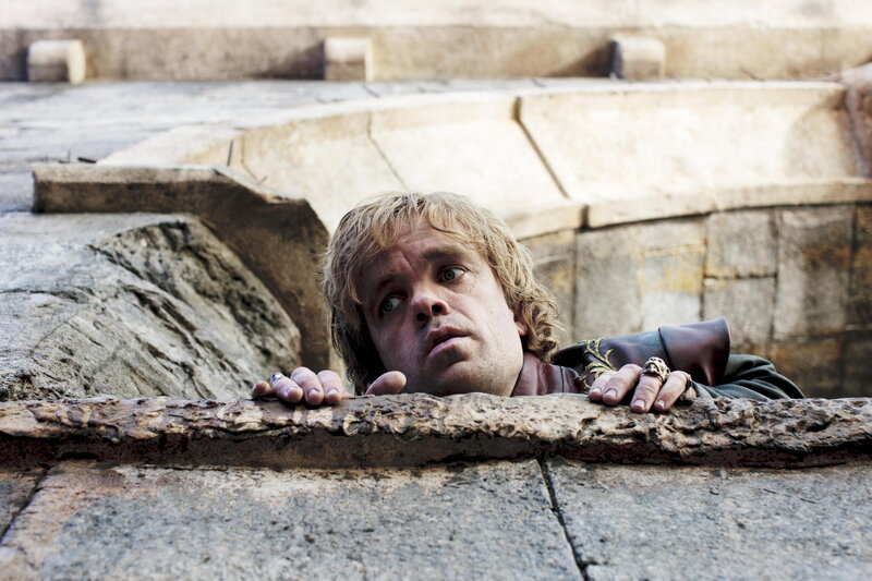 man peeking over stone wall
