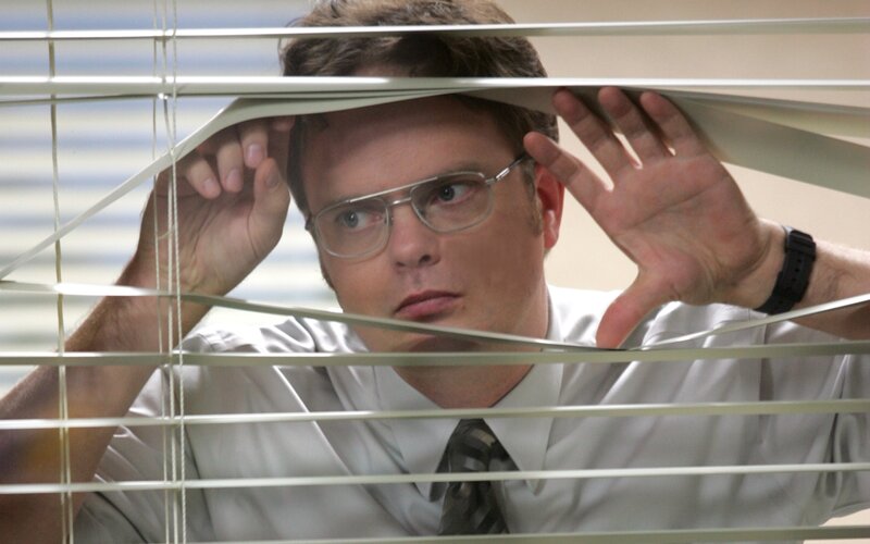 man peeking through blinds