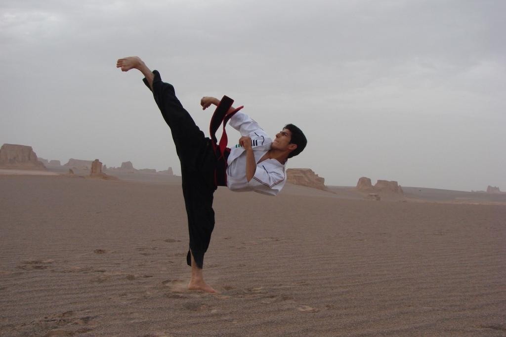 Man performing high kick in desert