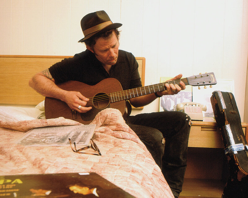 man playing acoustic guitar on bed