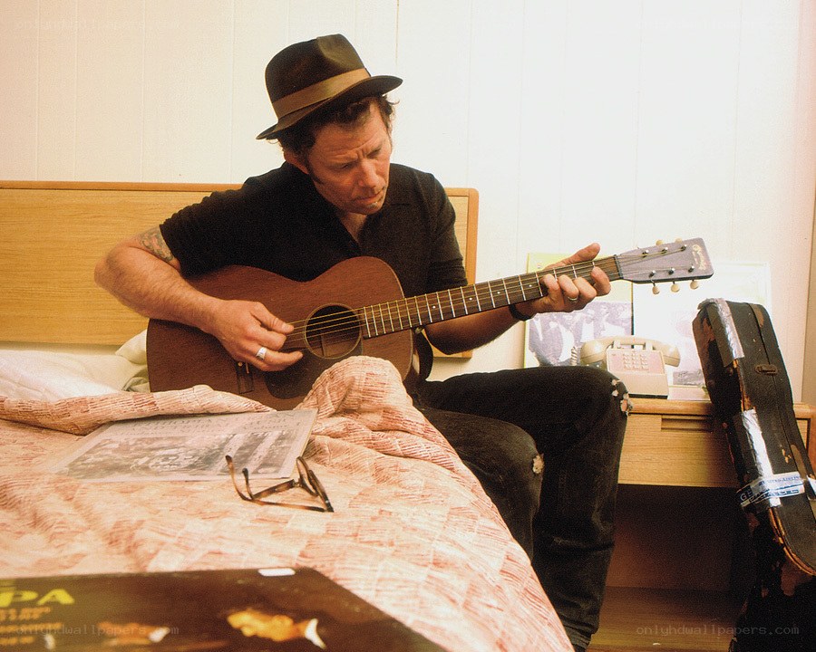 man playing acoustic guitar on bed