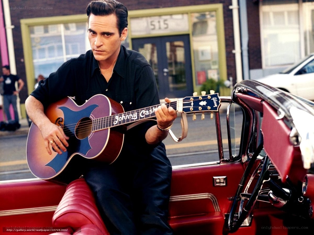 man playing guitar in red car