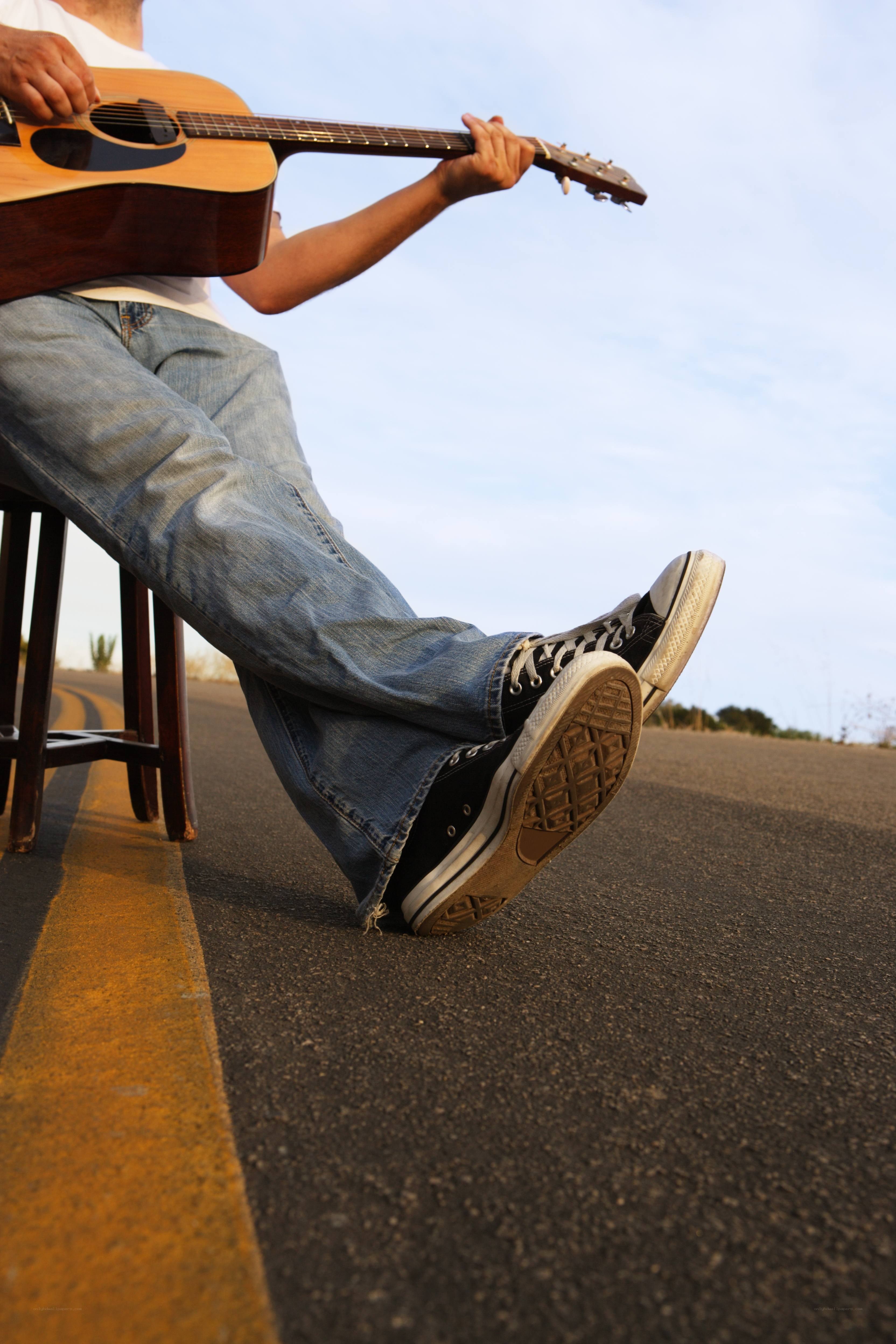man playing guitar on road