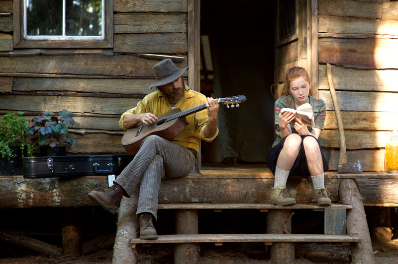 Man playing guitar with girl reading