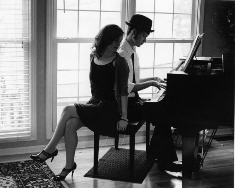 Man playing piano with woman beside him